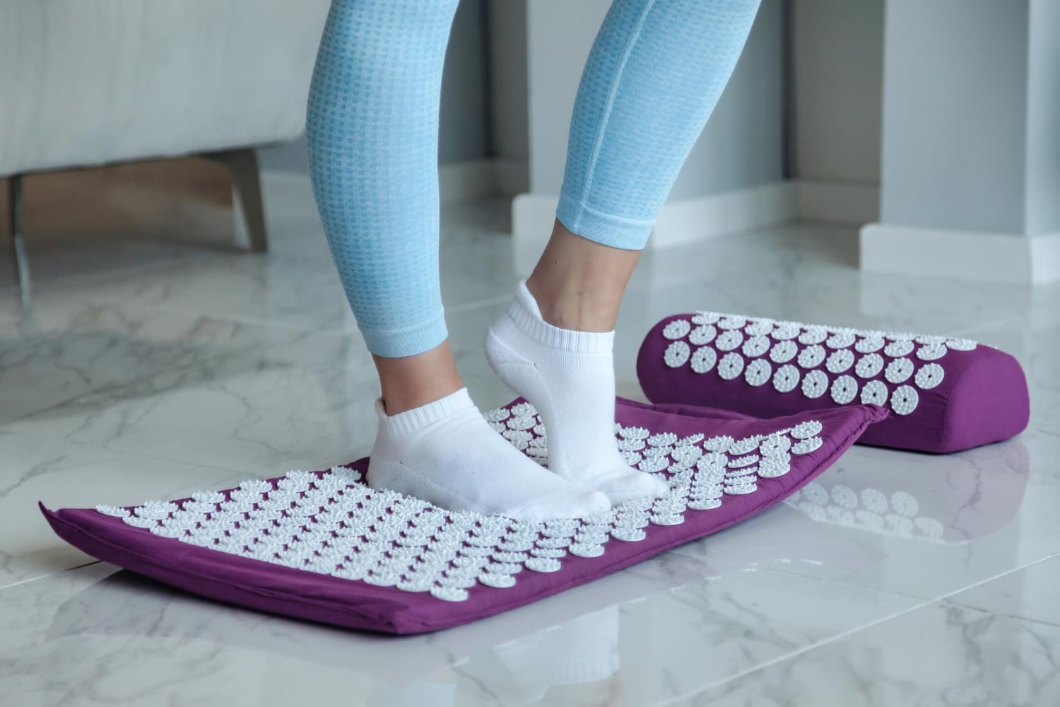femme utilise un tapis d'acupression pour soulager ses jambes