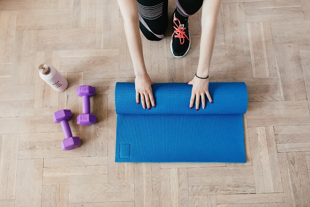 Illustration sport pour maigrir Personne qui roule son tapis de sport car elle vient de finir sa séance, elle a ses altères et sa bouteille d'eau avec elle, elle s'est mise au sport pour maigrir